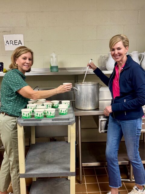 A volunteer serves a bowl of soup to a guest